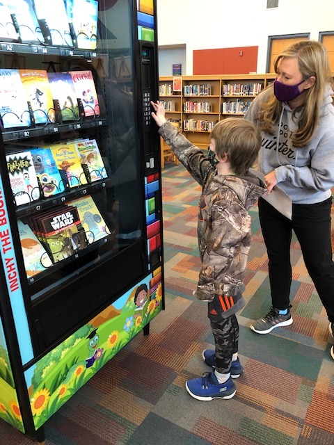 SHES student using the Book Vending Machine with a staff member assisting
